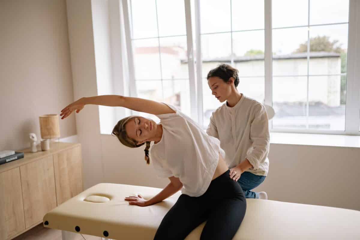 Massageterapeut hjälper patient att stretcha ryggen